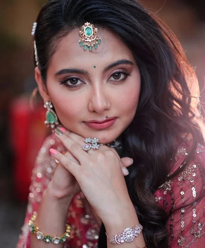 A face framed by a green stone maang tikka